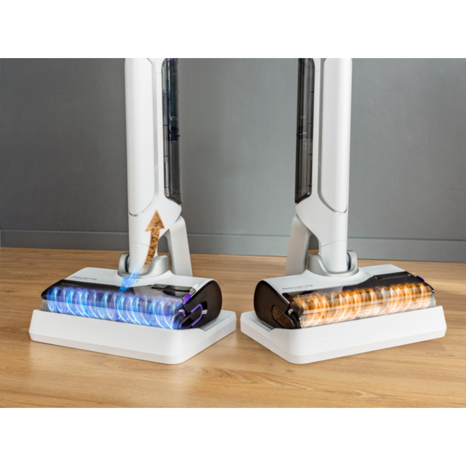 Two white vacuum cleaner heads. One side shows blue light, the other orange. Wooden floor.