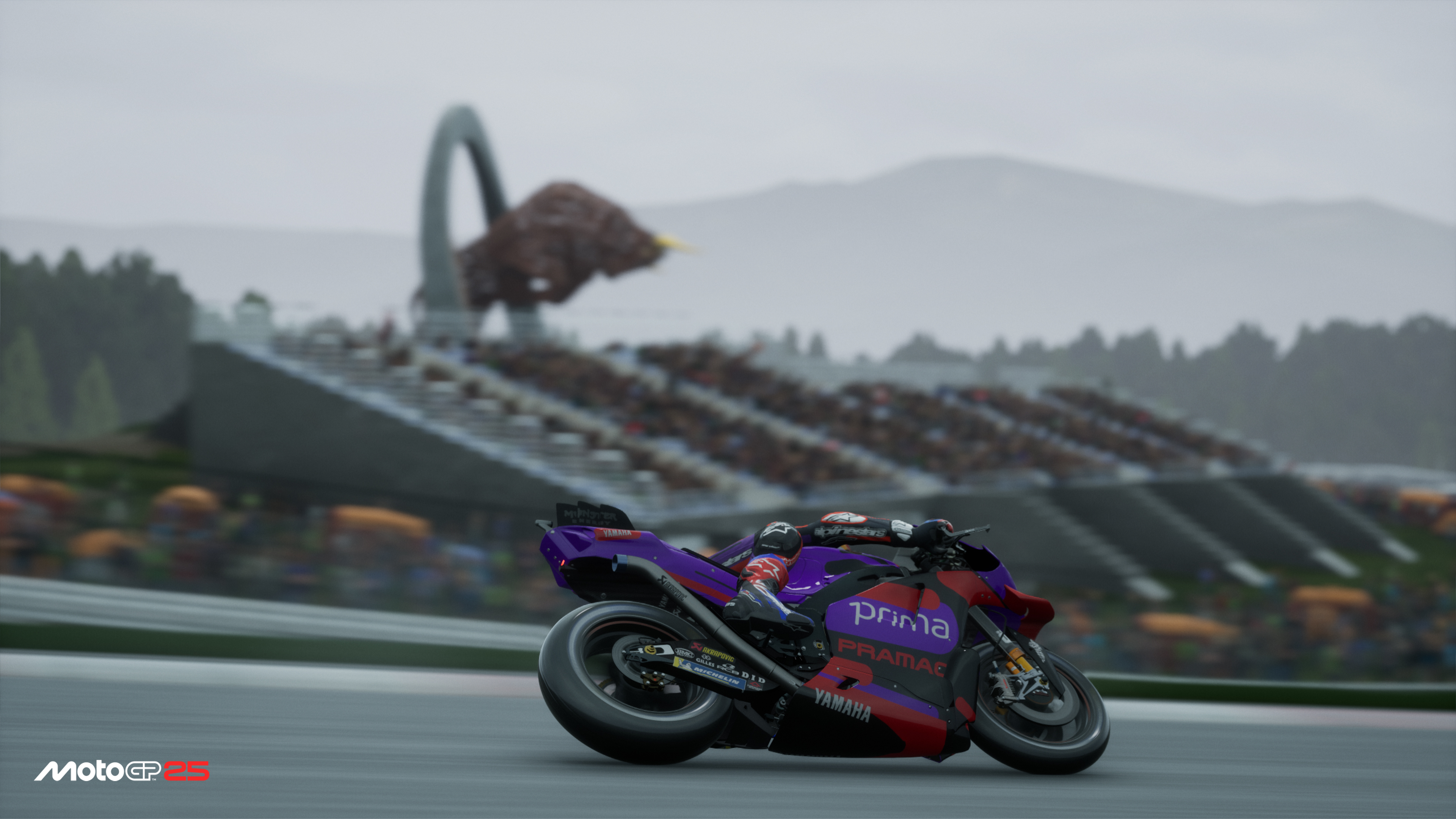 Ein Rennmotorrad auf einer Rennstrecke mit einem Stadion im Hintergrund, unscharf dargestellt.