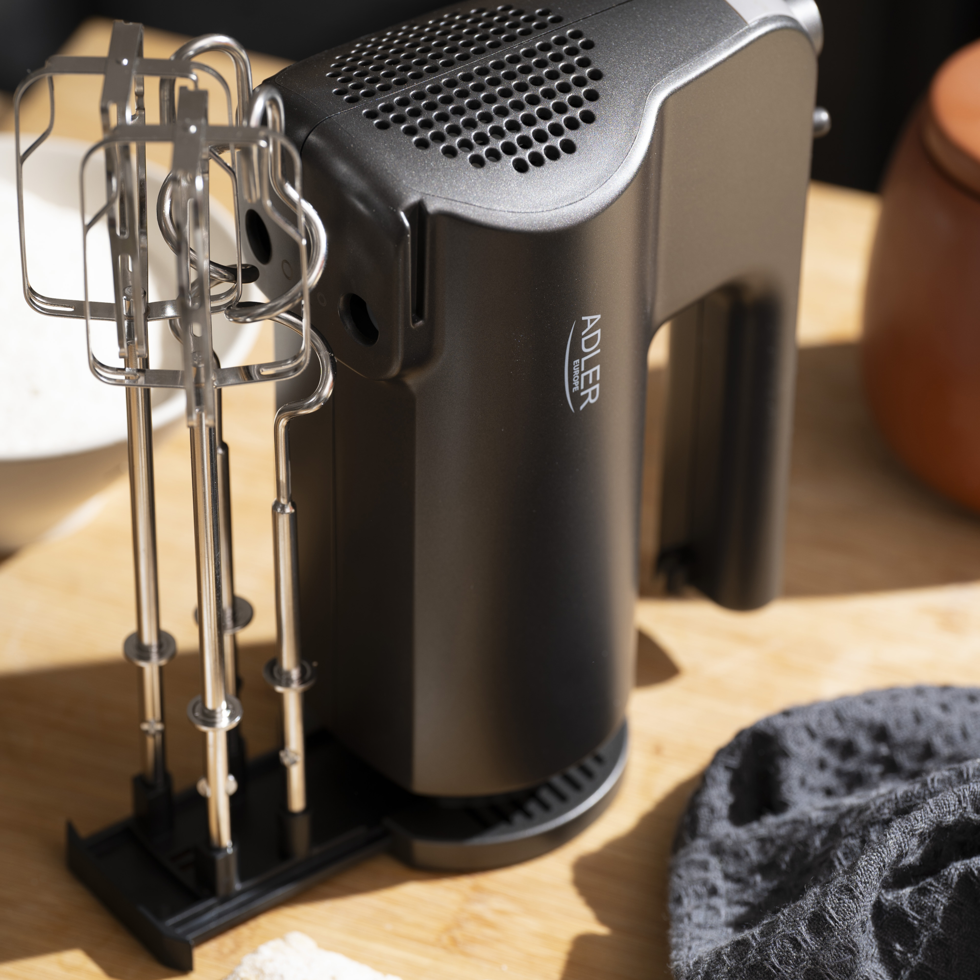 Fekete kézi mixer tartozékokkal, fa felületen, hozzávalókkal.