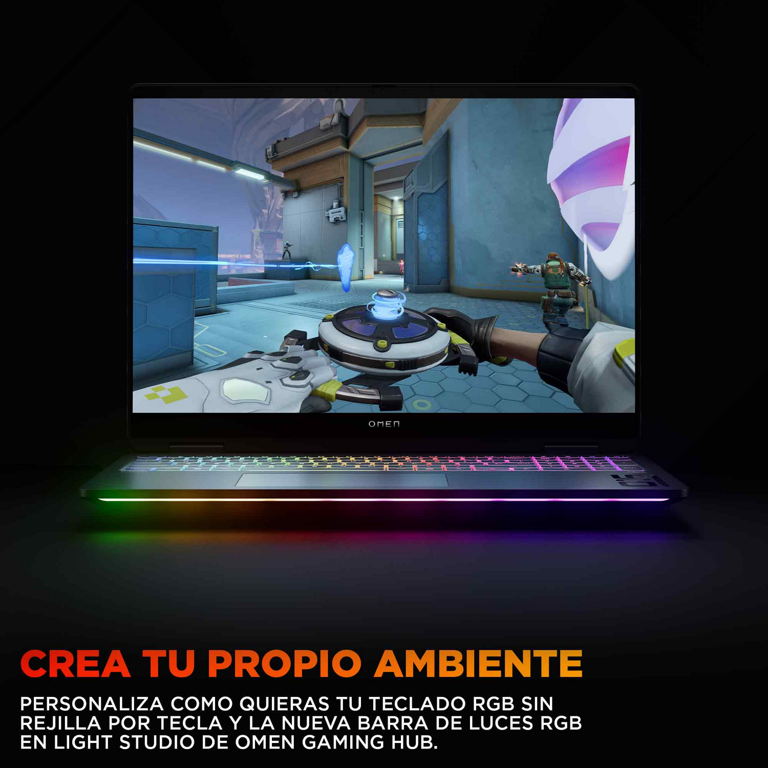Un portátil negro con un teclado arcoíris brillante. La pantalla muestra un juego. El texto de abajo dice 'Crea tu propio ambiente'.