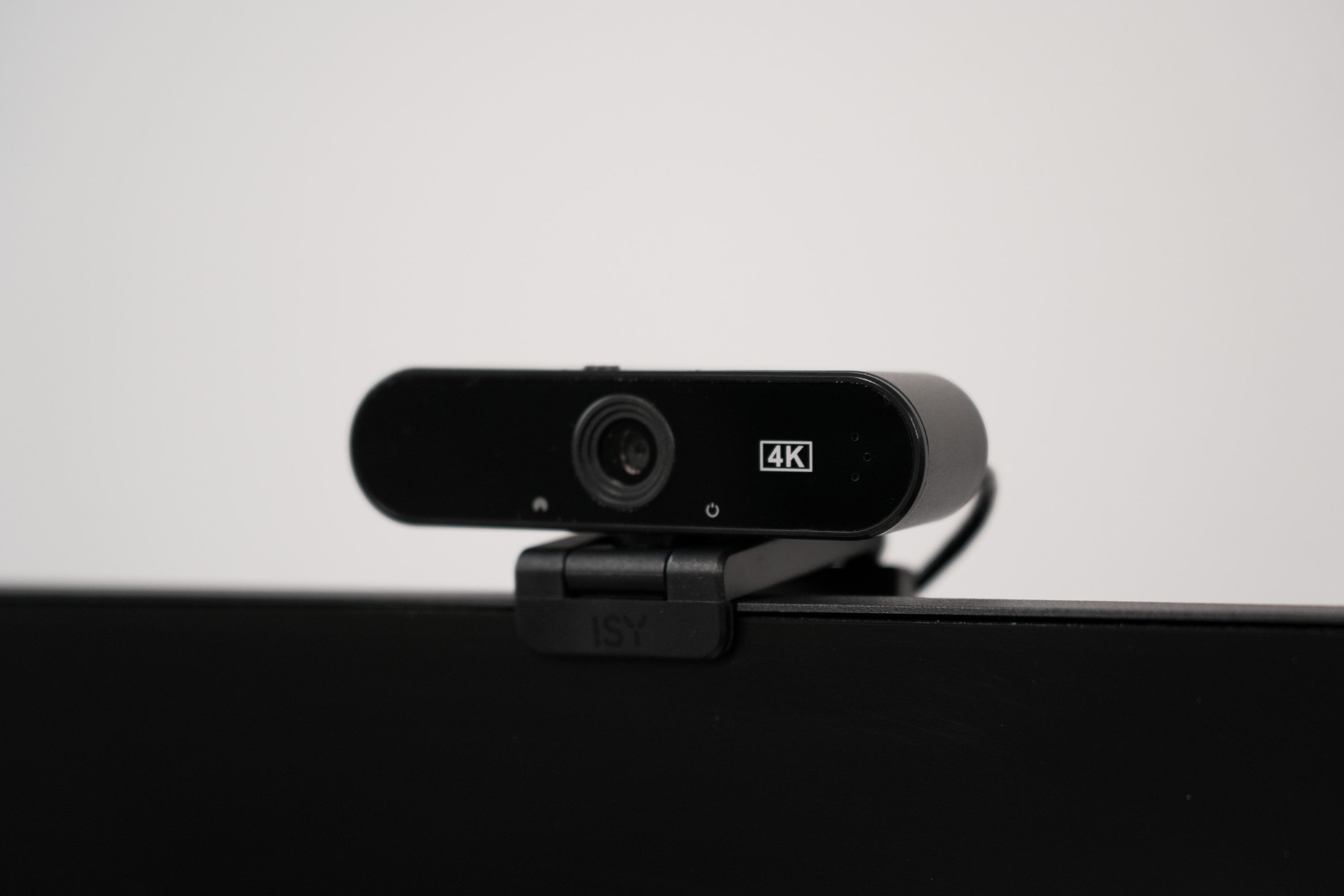 Czarna kamera internetowa na czarnym monitorze, pod kątem z jasnym tłem.