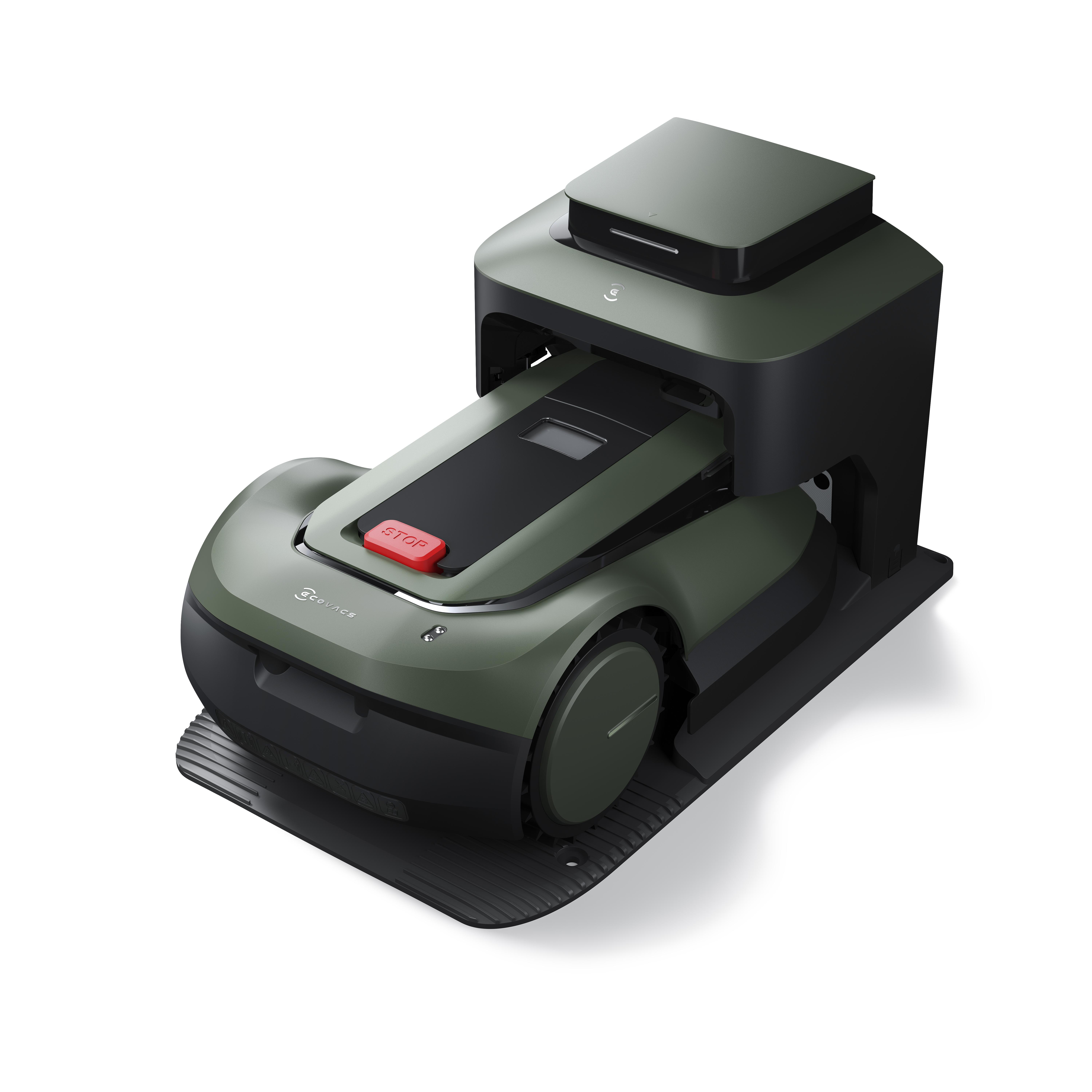 Ein olivgrüner Roboter-Rasenmäher auf einer schwarzen Matte, mit rotem „STOP“-Knopf. Weißer Hintergrund.