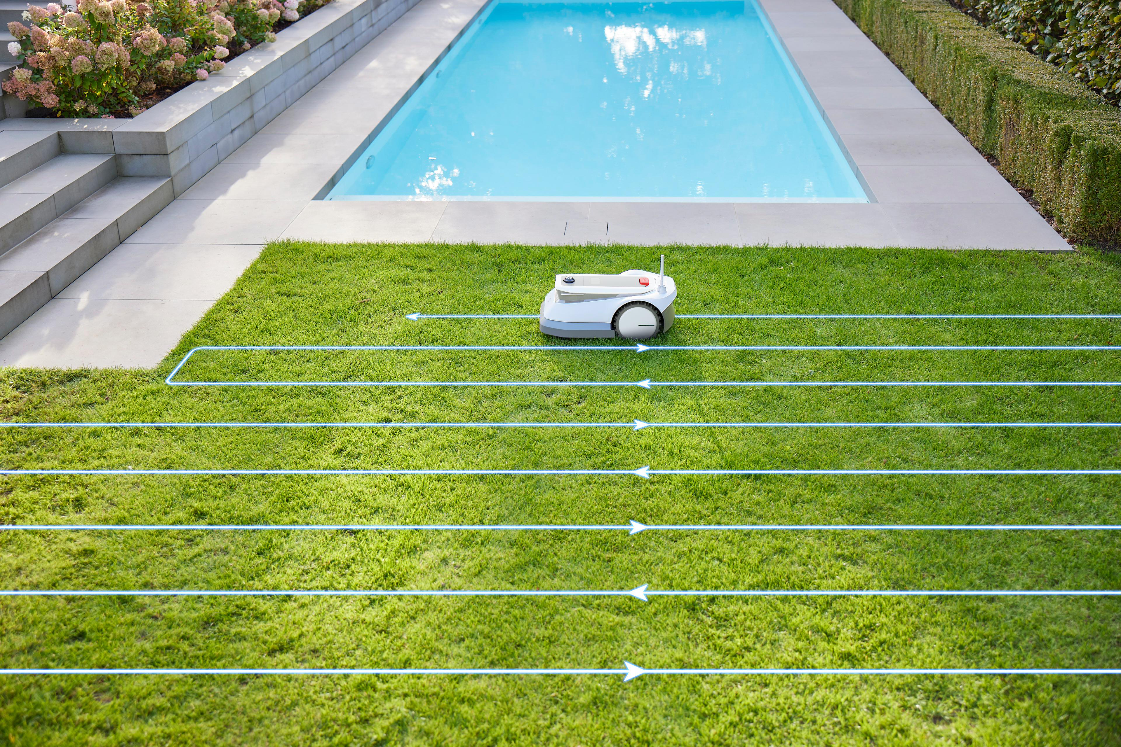 Ein Rasenroboter auf Gras, der einem geplanten Schneidemuster folgt, mit einem Swimmingpool im Hintergrund.