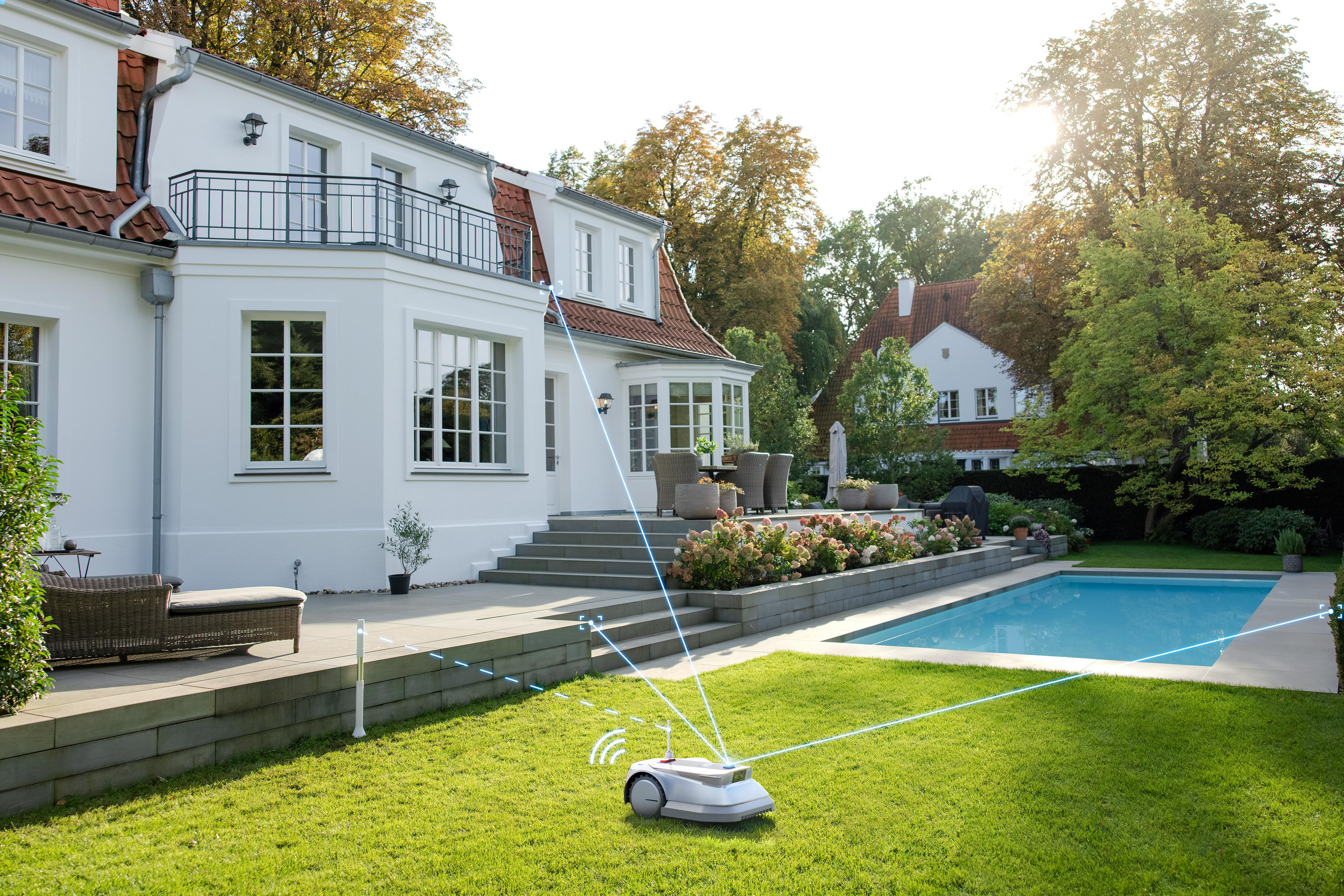 Ein weißes Haus mit Pool und Rasenmähroboter.