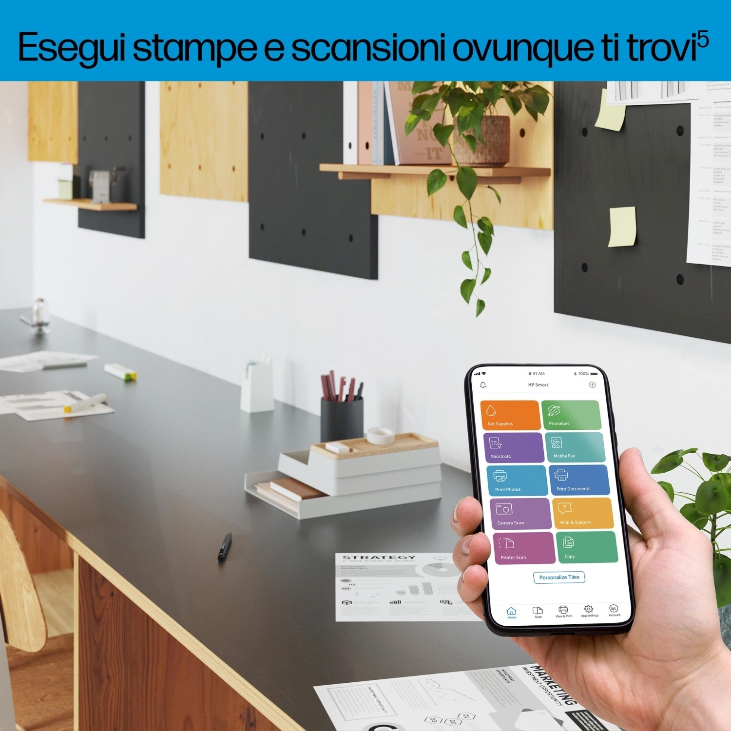 Una mano che tiene uno smartphone che mostra un'applicazione di stampa e scansione, vicino a un tavolo.