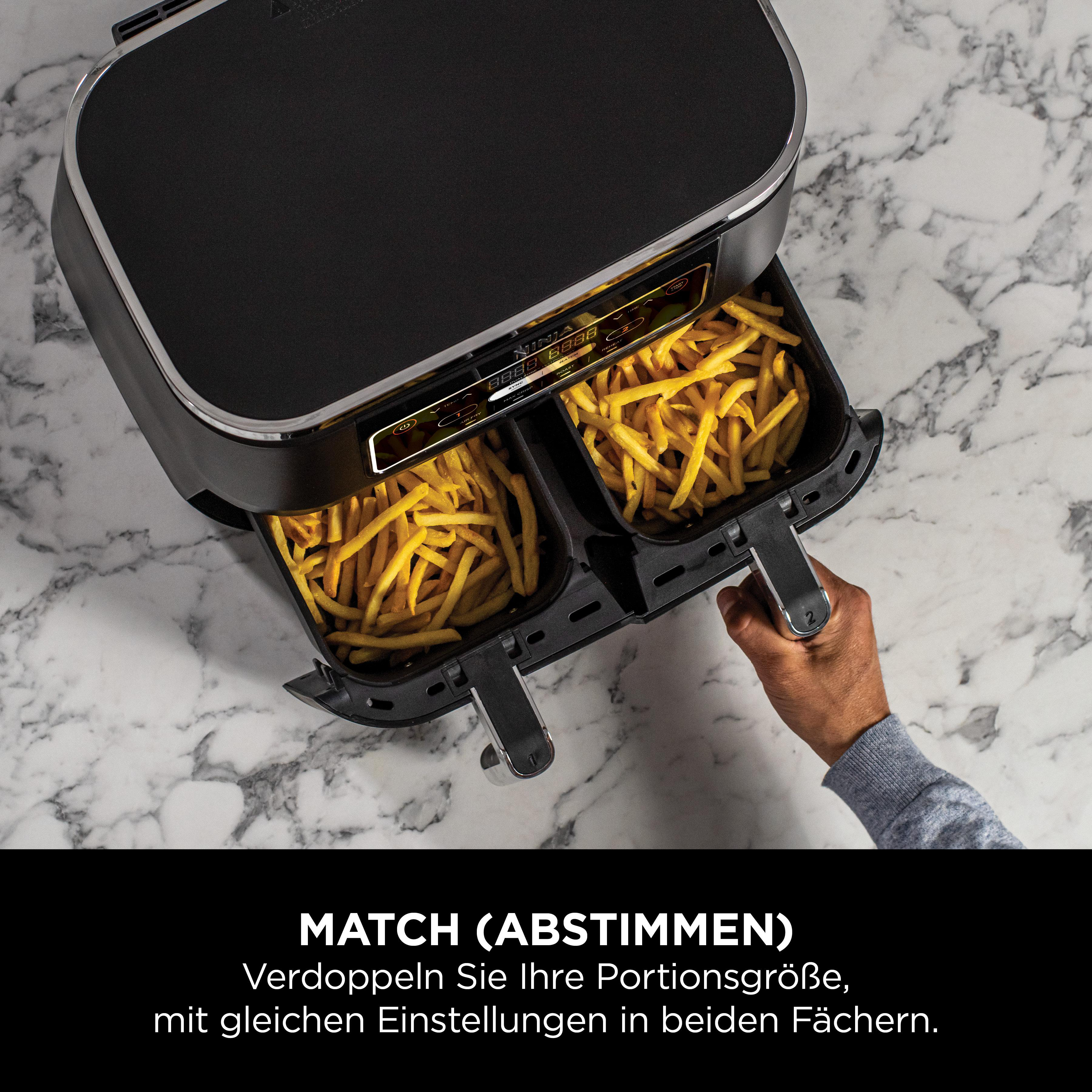 Heißluftfritteuse mit zwei Fächern, gefüllt mit Pommes. Eine Hand greift nach der Fritteuse.