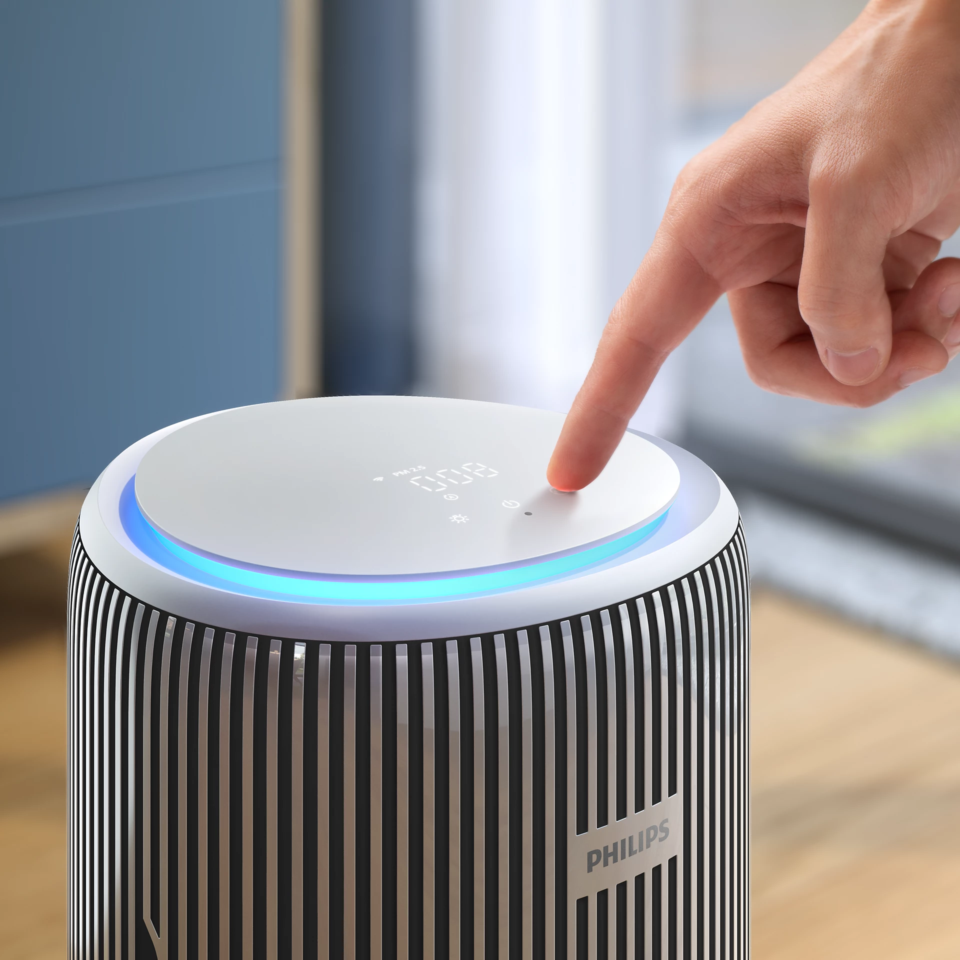 Une main appuie sur le bouton d'un purificateur d'air. Le purificateur est noir et blanc.