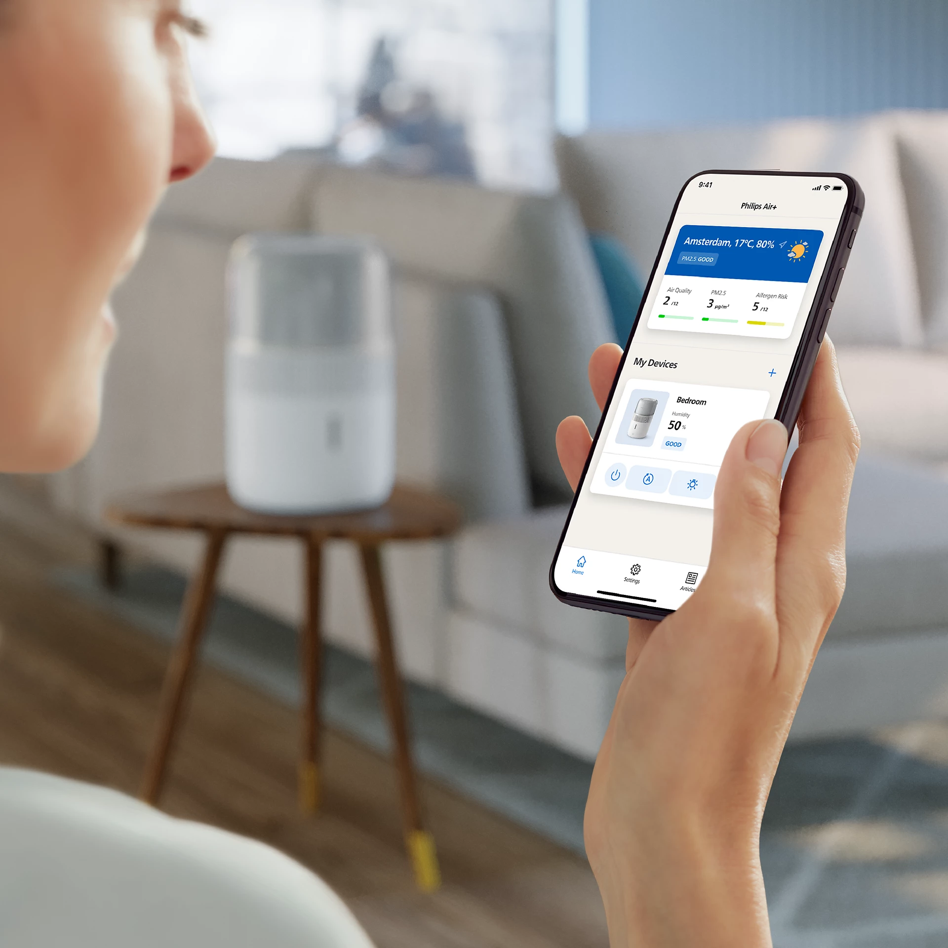 Femme tenant un téléphone avec une application de qualité de l'air. Purificateur d'air.