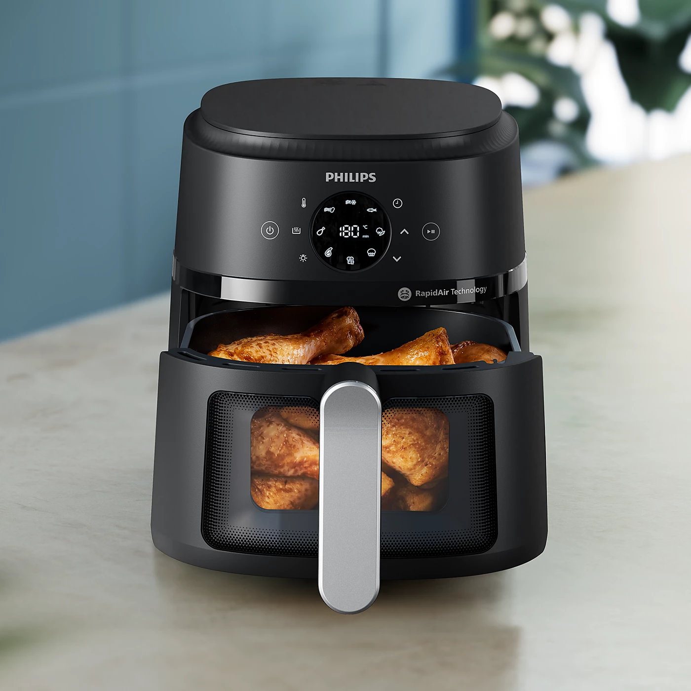 Un Philips Airfryer noir avec du poulet à l'intérieur. La température est réglée sur 180 degrés.