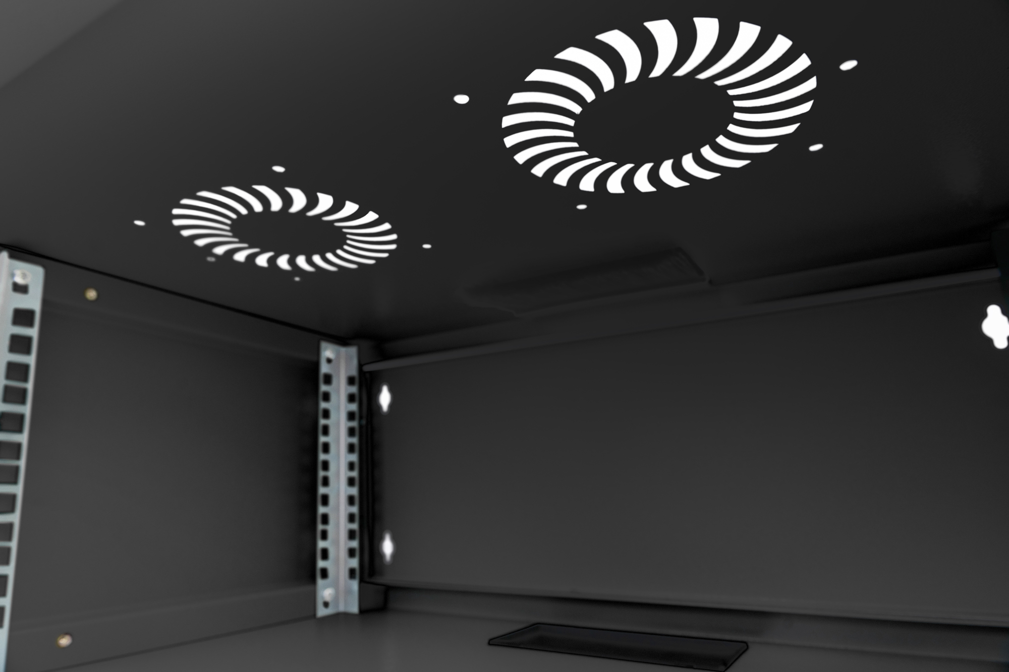 Innerhalb eines schwarzen Server-Racks. Zwei Lüfteröffnungen mit weißen Spiralmustern sichtbar.