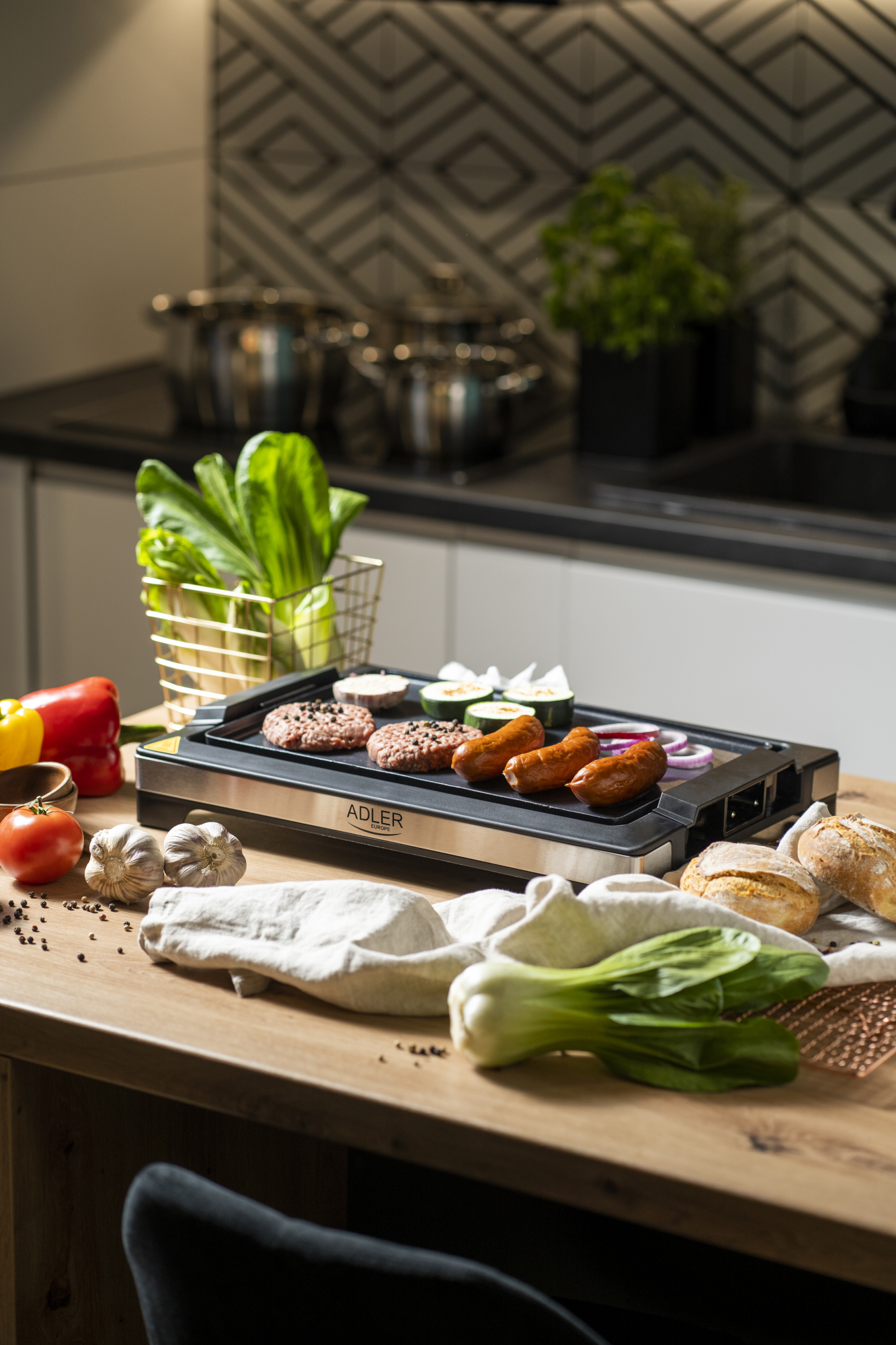 Grill ételekkel. Faasztalon zöldségek és készételek. Konyha a háttérben.