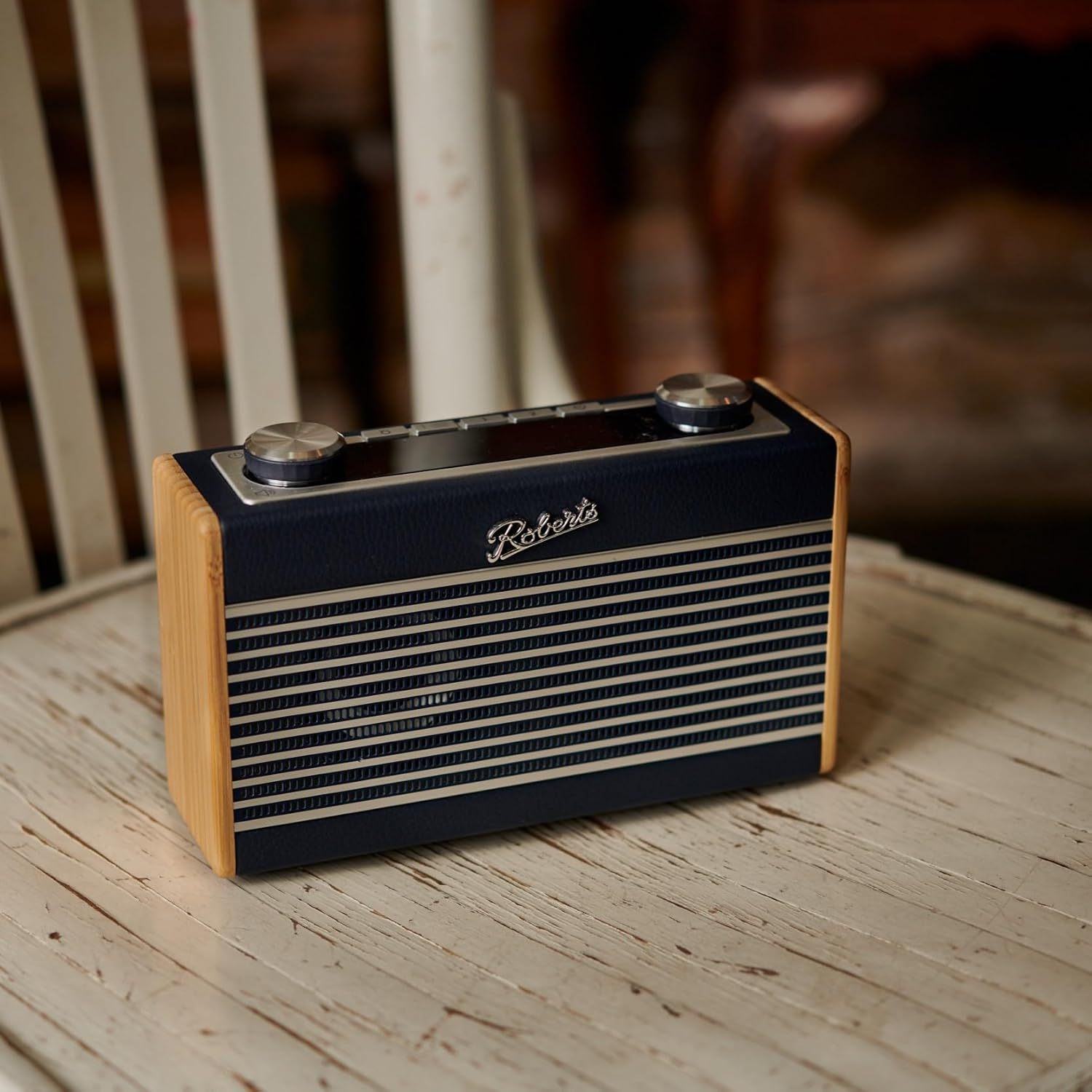 Retro Roberts Radio, Marineblau mit silbernen Details. Auf weißem Holzstuhl.