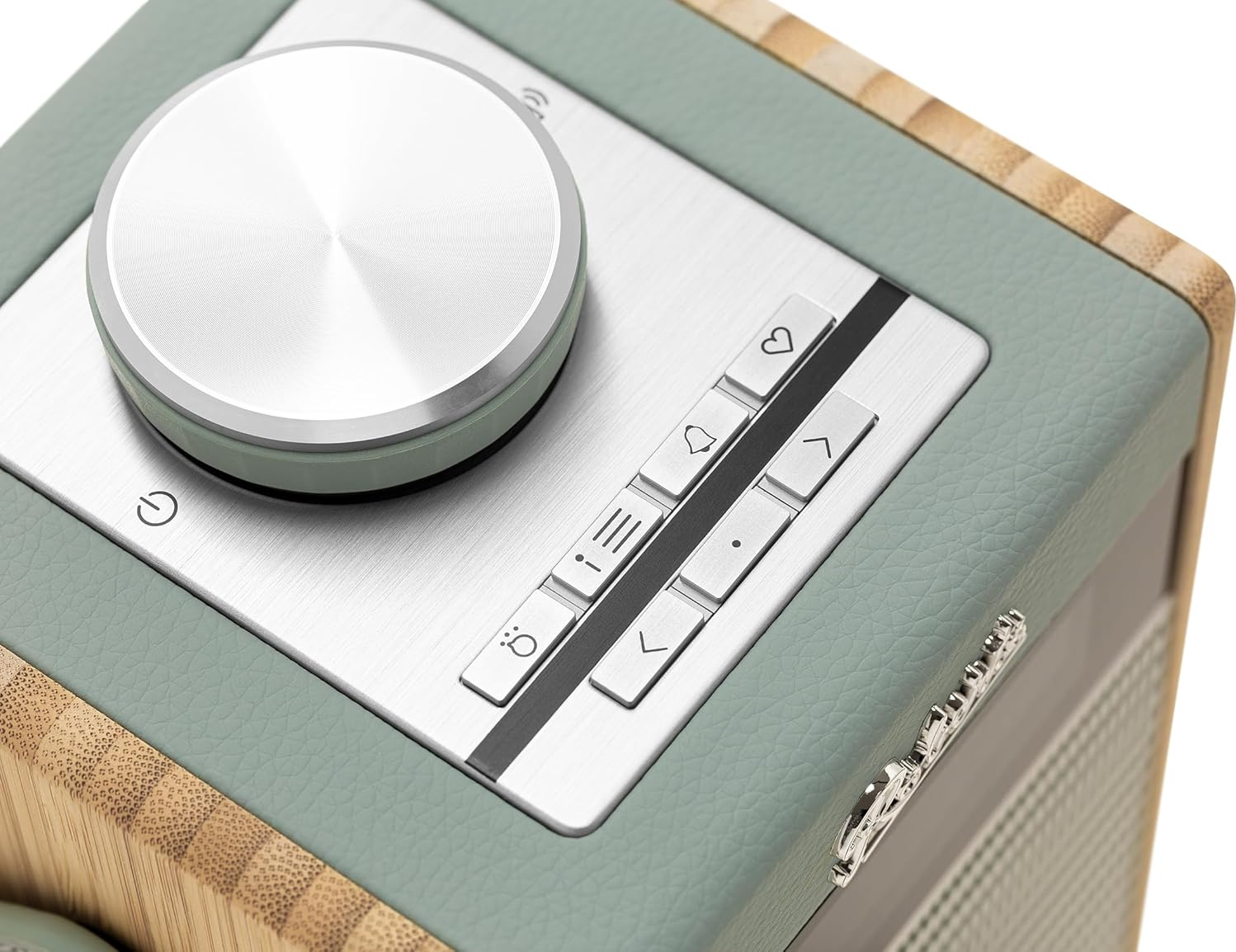 Nahaufnahme eines Radios mit Knöpfen und einem silbernen Bedienknopf. Grüne und Holzoberfläche.