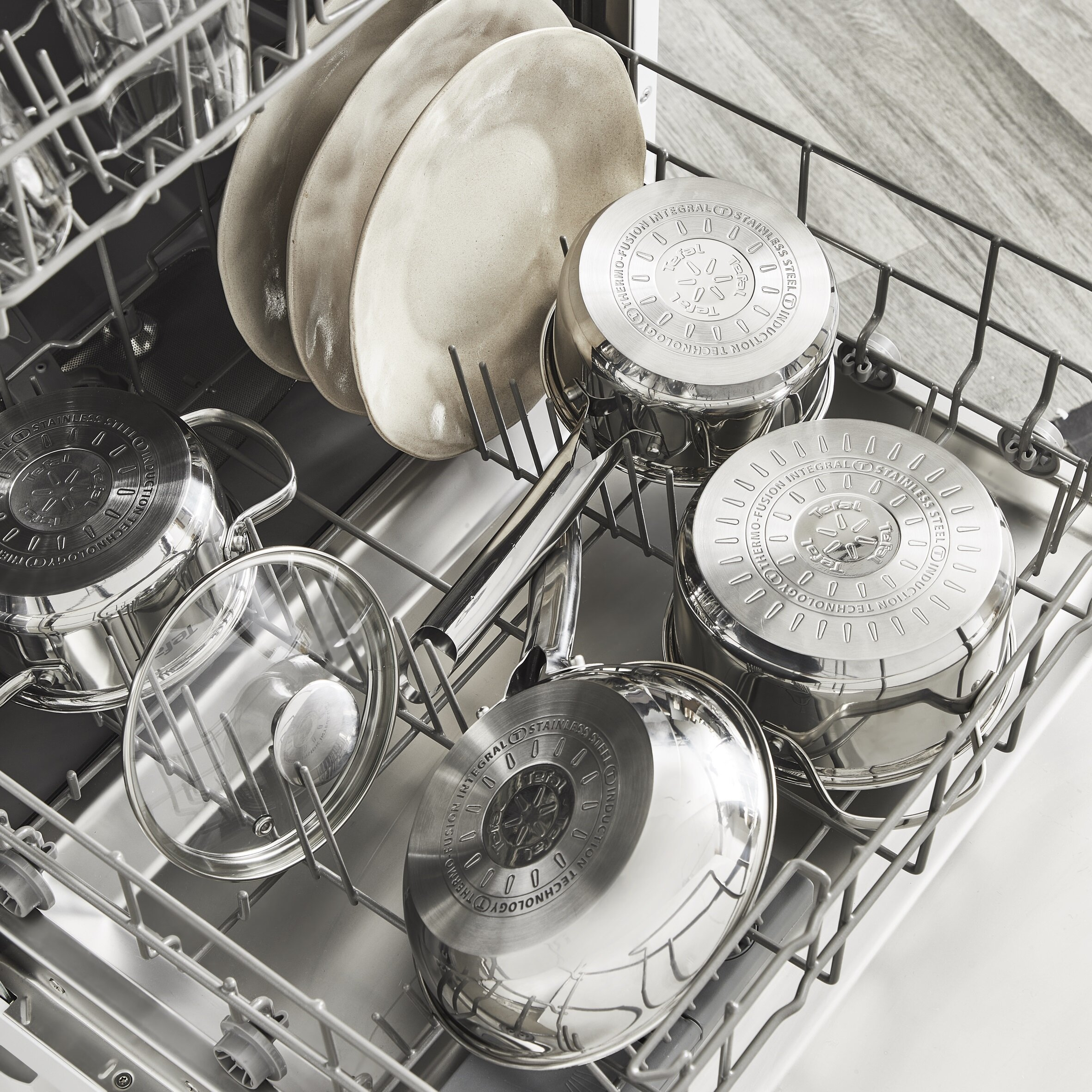 Wnętrze zmywarki z naczyniami i patelniami. Stal nierdzewna i kolory beżowe. Czysto i uporządkowanie.