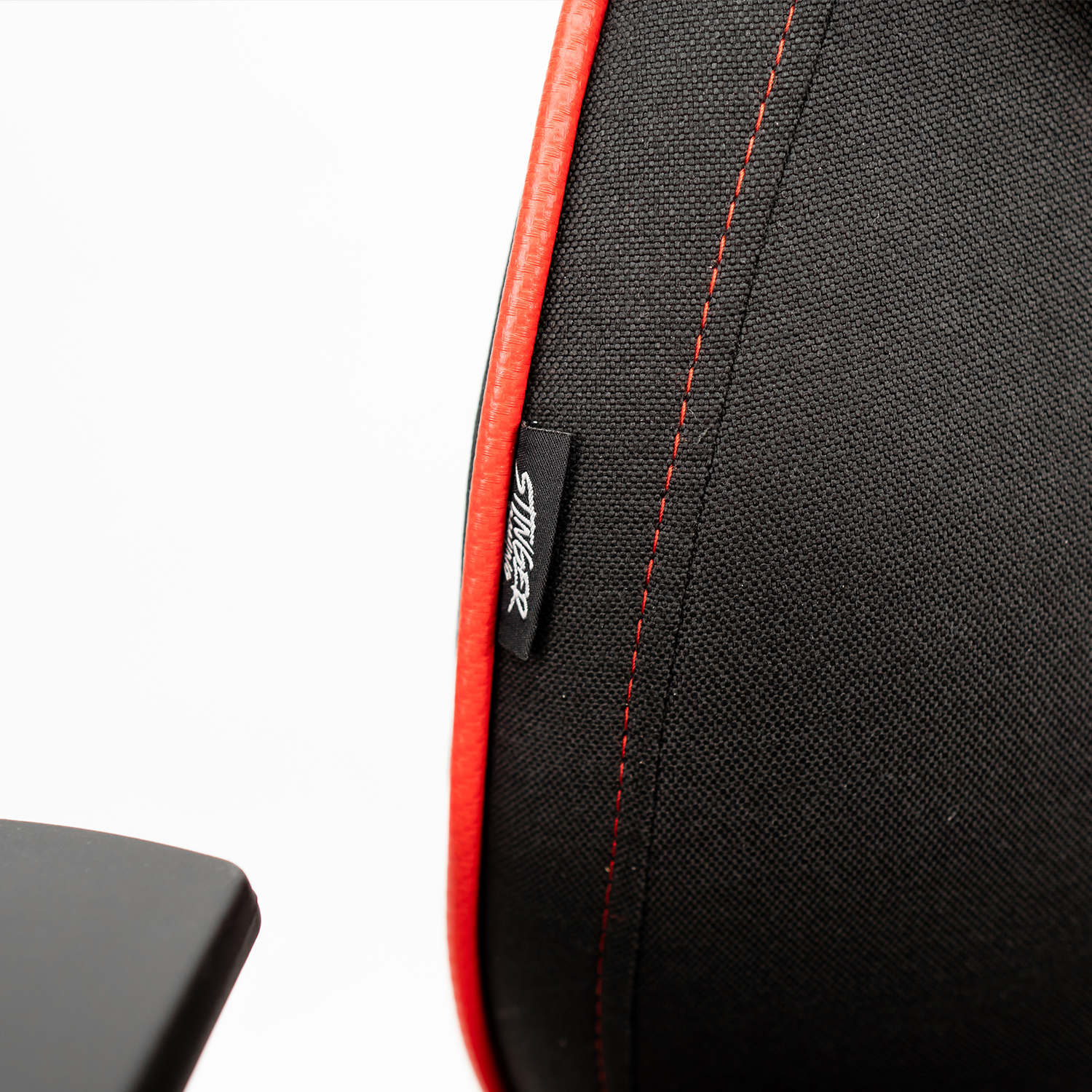 Primer plano de una silla gaming negra con costuras rojas y una pequeña etiqueta STINGER.