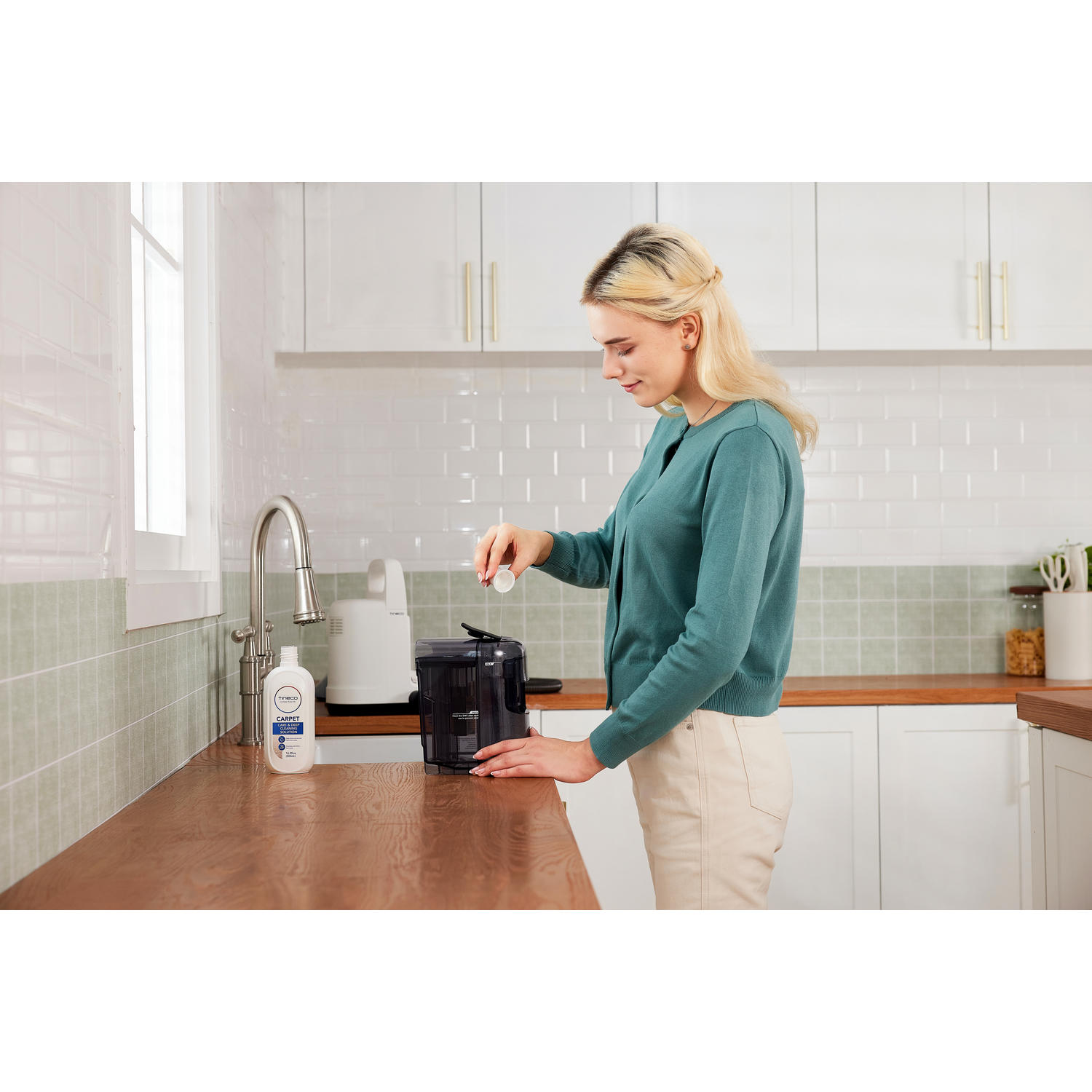 Woman in kitchen adding tablet to a container. Wooden counter, white cabinets.
