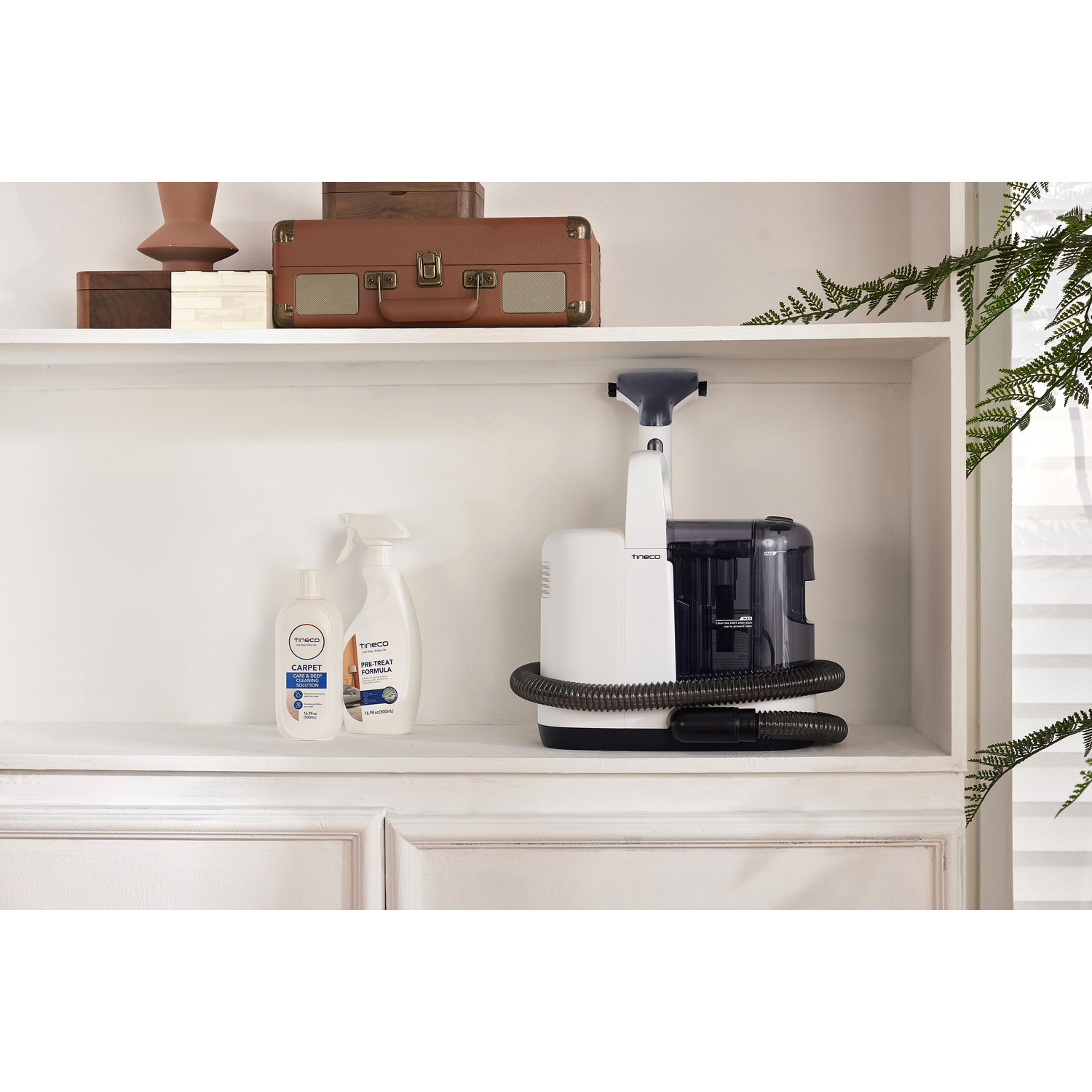 A white and black carpet cleaner and cleaning supplies on a shelf.