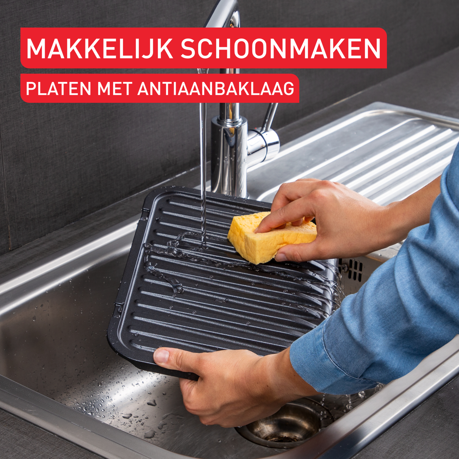 Een persoon wast een zwarte, geribbelde grillplaat in een gootsteen met een spons.