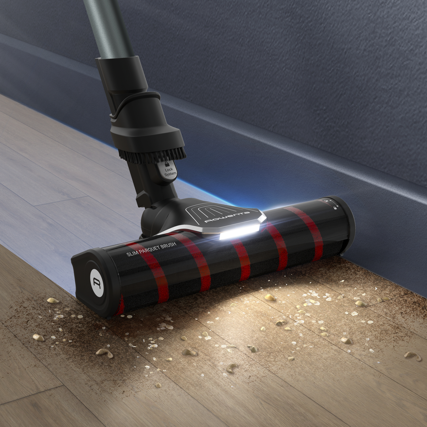 A black and red vacuum cleaner head cleaning a wood floor. Debris is scattered on the floor.