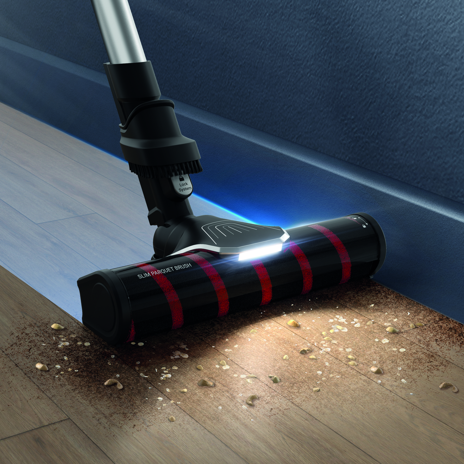 Vacuum cleaner head in use, cleaning a wooden floor, with debris.