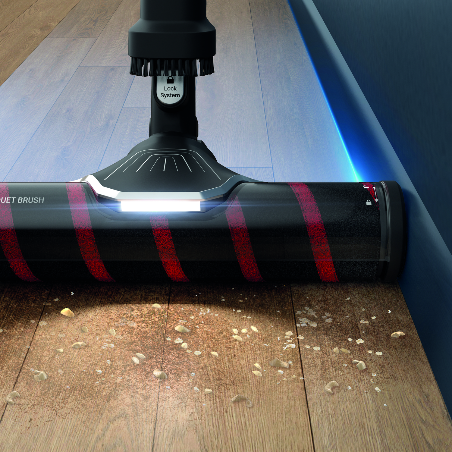A vacuum cleaner head cleaning a wooden floor. The brush is red and black.