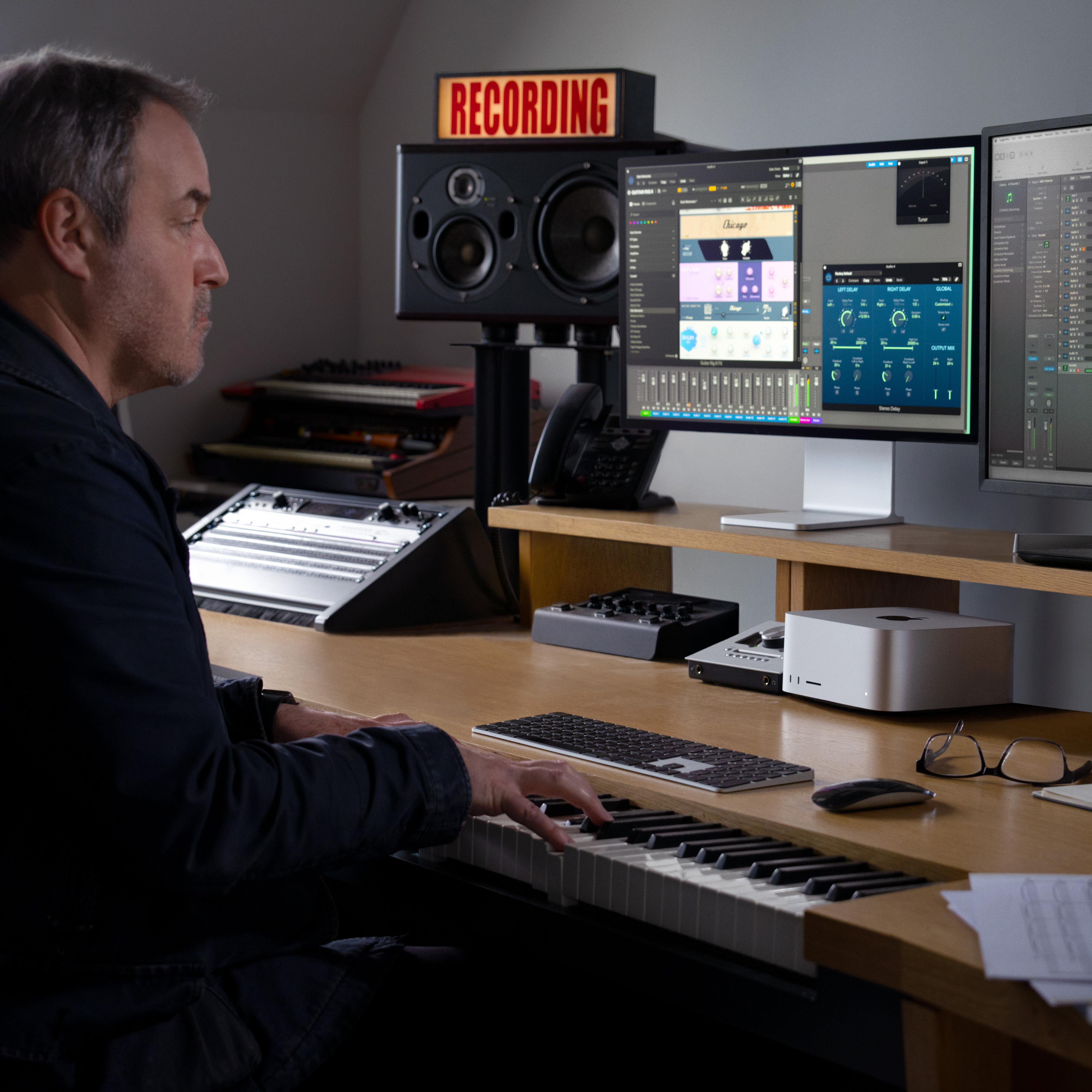 Ein Mann spielt Keyboard in einem Aufnahmestudio. Es gibt Computerbildschirme.