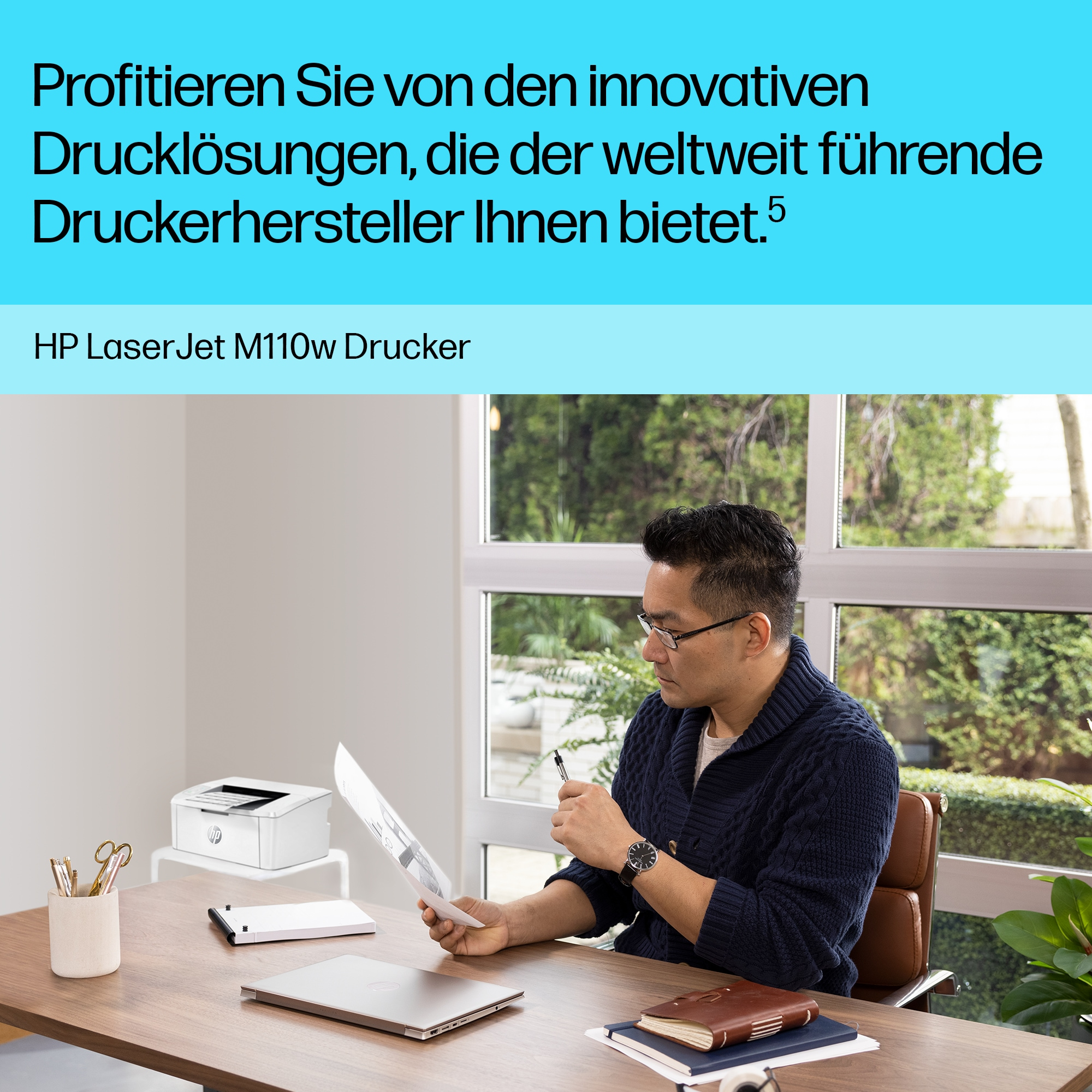 Mann mit Brille betrachtet Papiere an einem Schreibtisch. Drucker und Bürobedarf sind vorhanden.