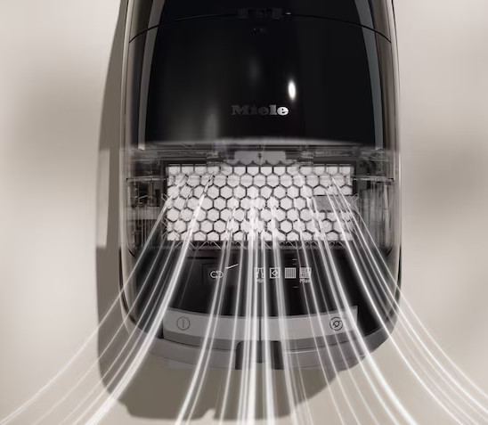 Zbliżenie przodu odkurzacza. Smugi światła z maszyny. Widoczne słowo Miele.