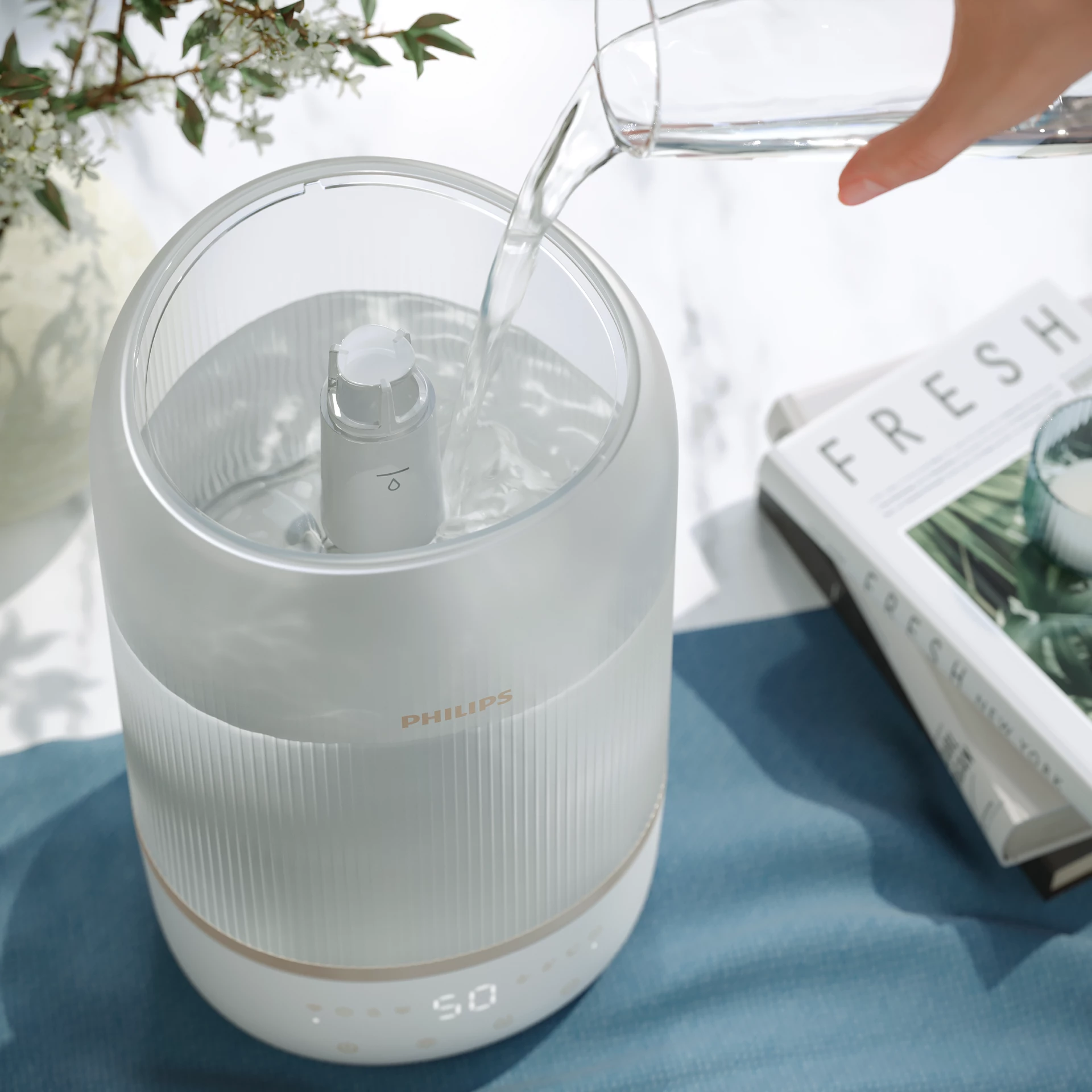 Un umidificatore viene riempito con acqua. Acqua limpida viene versata in un dispositivo bianco e trasparente.