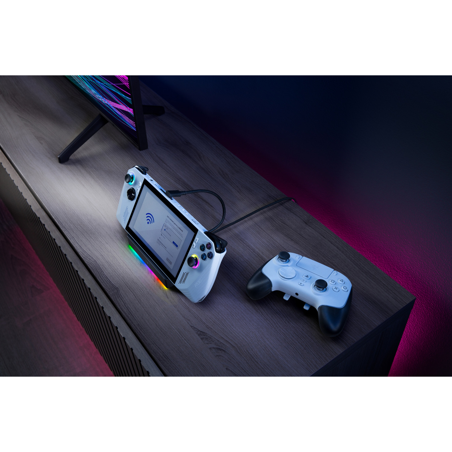 Gaming console and controller on a table, with a TV in the background, dark theme.