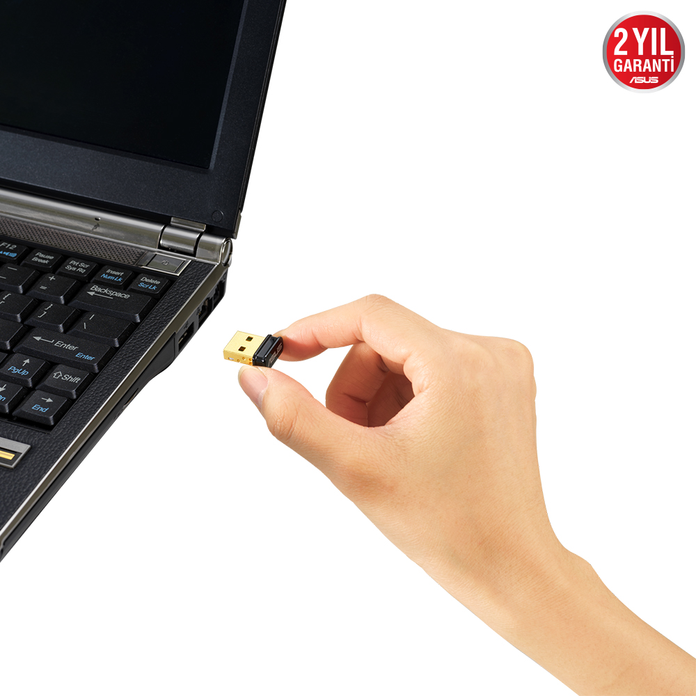 Bir el, bir dizüstü bilgisayar klavyesinin yanında altın bir USB sürücü tutuyor.