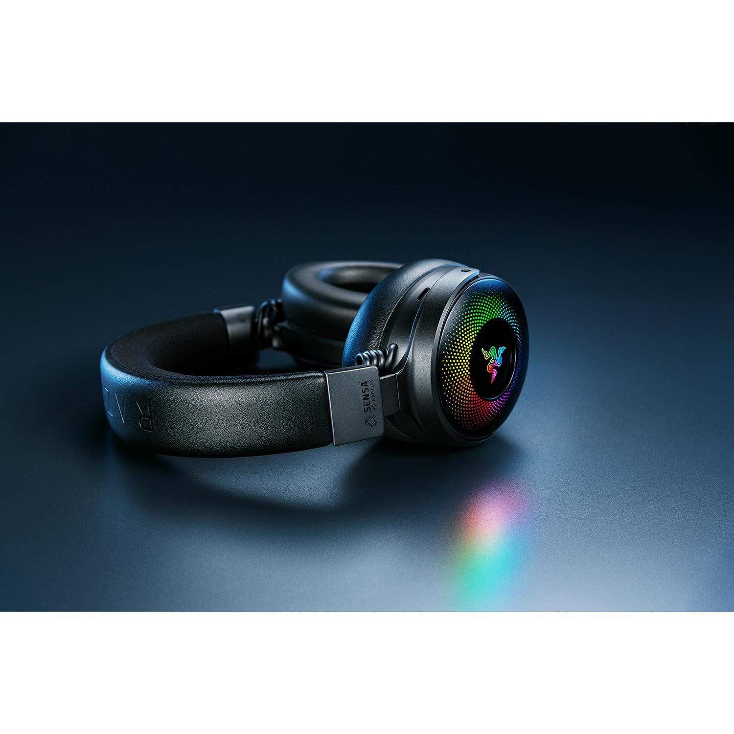 Casque Razer noir sur une surface sombre. L'écouteur affiche un logo arc-en-ciel.