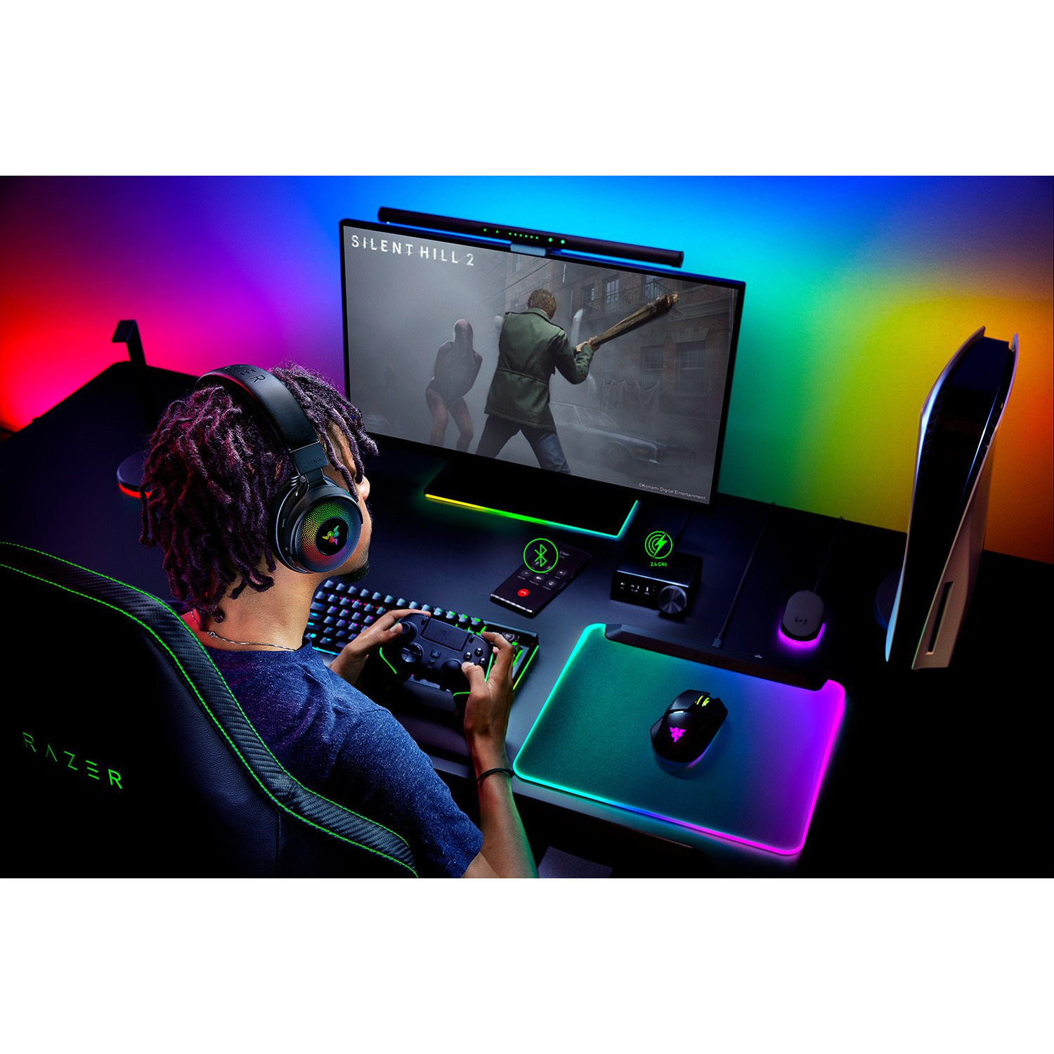 Une personne avec un casque joue. Un moniteur affiche une scène de jeu, une PS5 est visible.