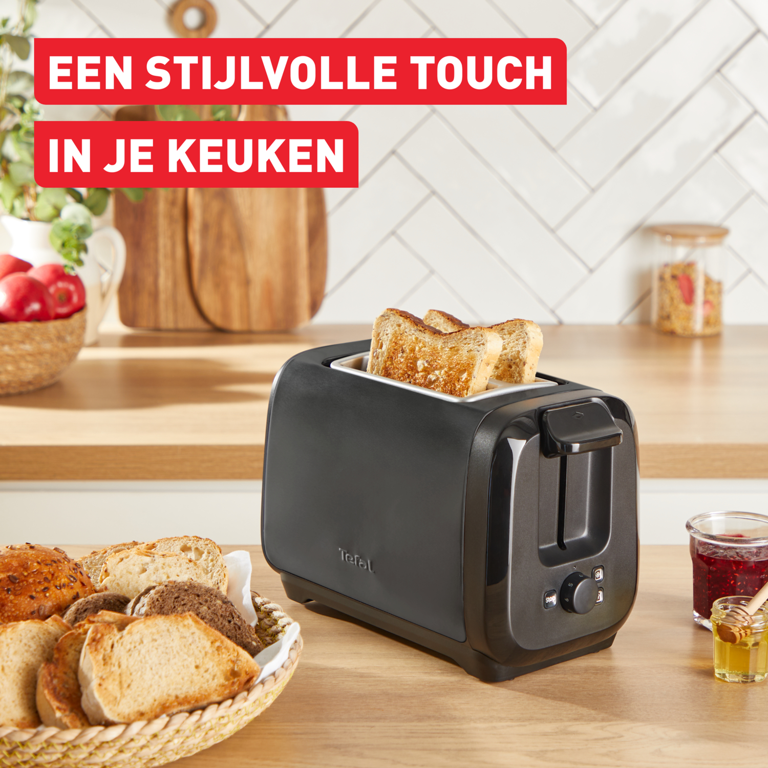 Een zwarte broodrooster met toast, een pot jam en honing op een houten snijplank.