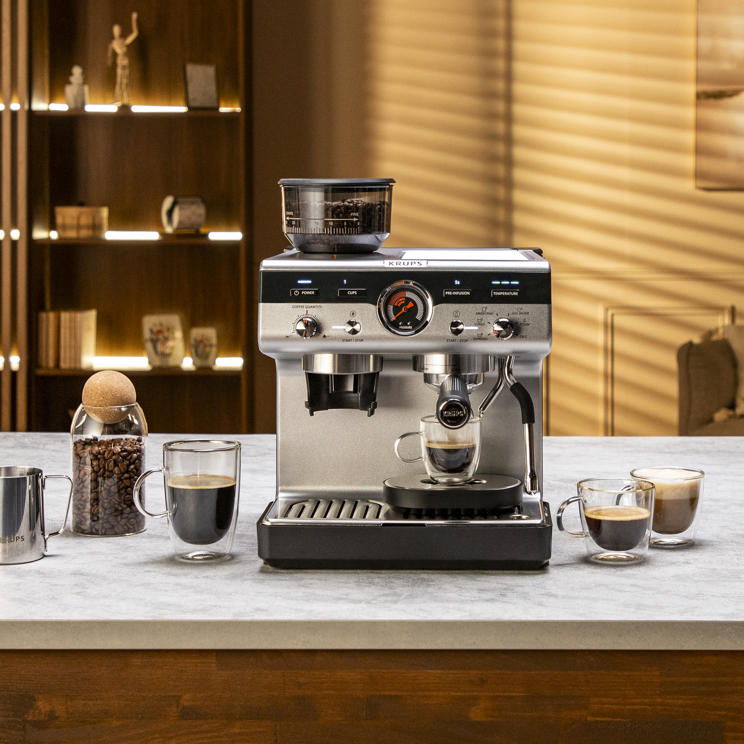 Espresso machine with coffee, glasses, and coffee beans in jar on a counter.