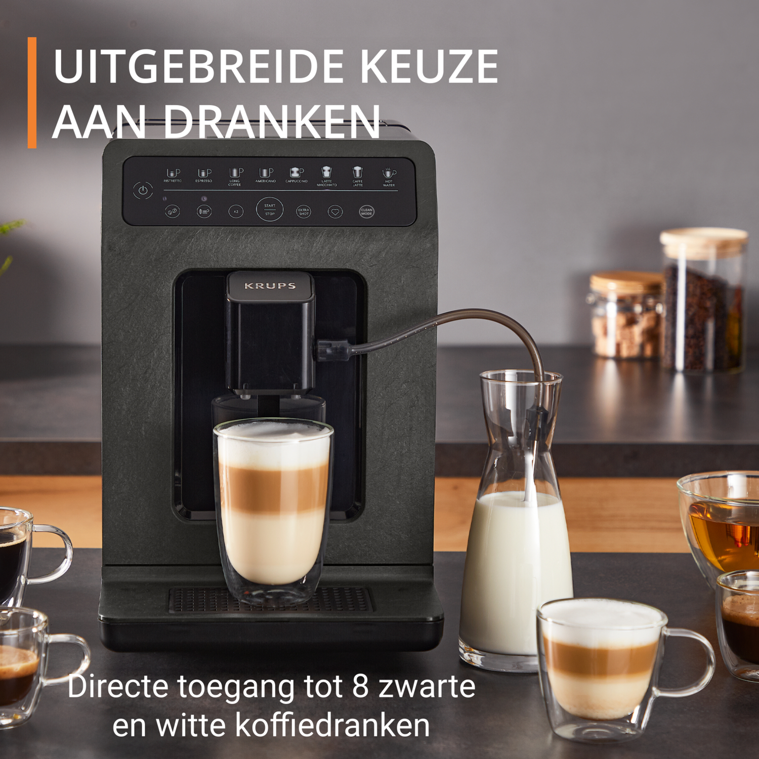 Een koffiemachine met kopjes en een glazen kan met melk, naast verschillende koffiedranken. Tekst in het Nederlands.
