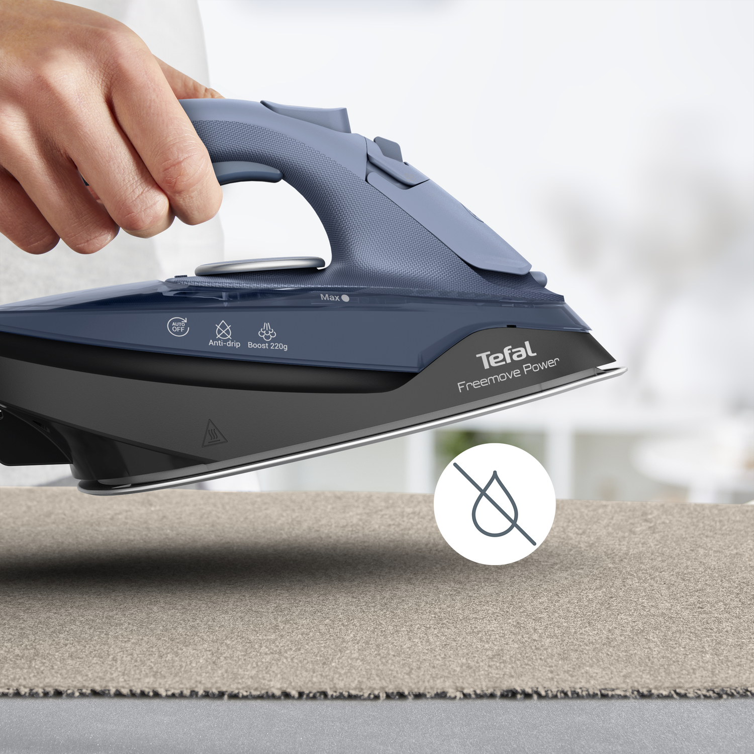 A person ironing a beige fabric with a blue and black iron.