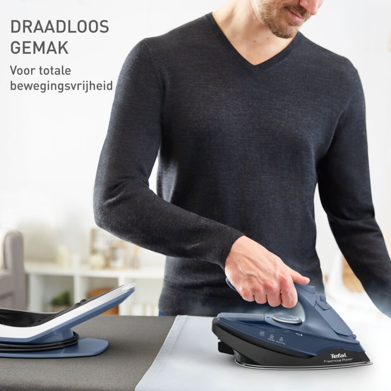 A man ironing a white shirt on an ironing board with a blue and black iron.
