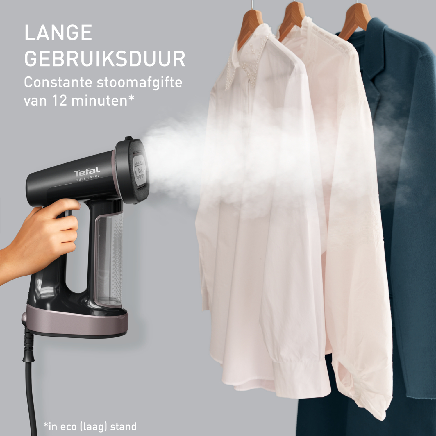 Hand holding a black Tefal Pure Force steamer, steaming white shirts and a coat.
