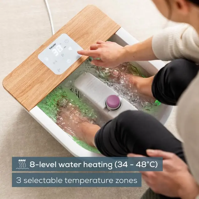 Person benutzt ein Fußbad mit Wasser. Das Bad hat Holzverkleidung und ein digitales Display.