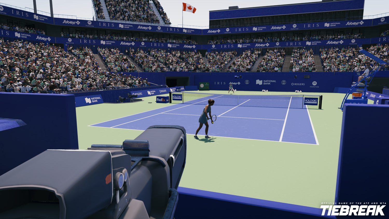 Vista de la cancha de tenis durante un partido, con jugadores y público. Una cámara en primer plano.