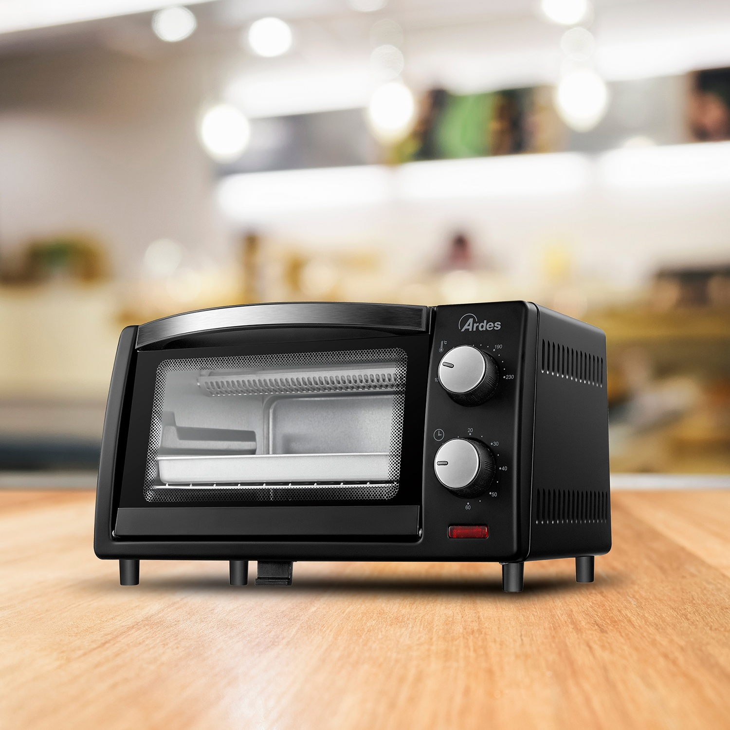Un forno tostapane nero è su un tavolo di legno, con due manopole e una porta di vetro.