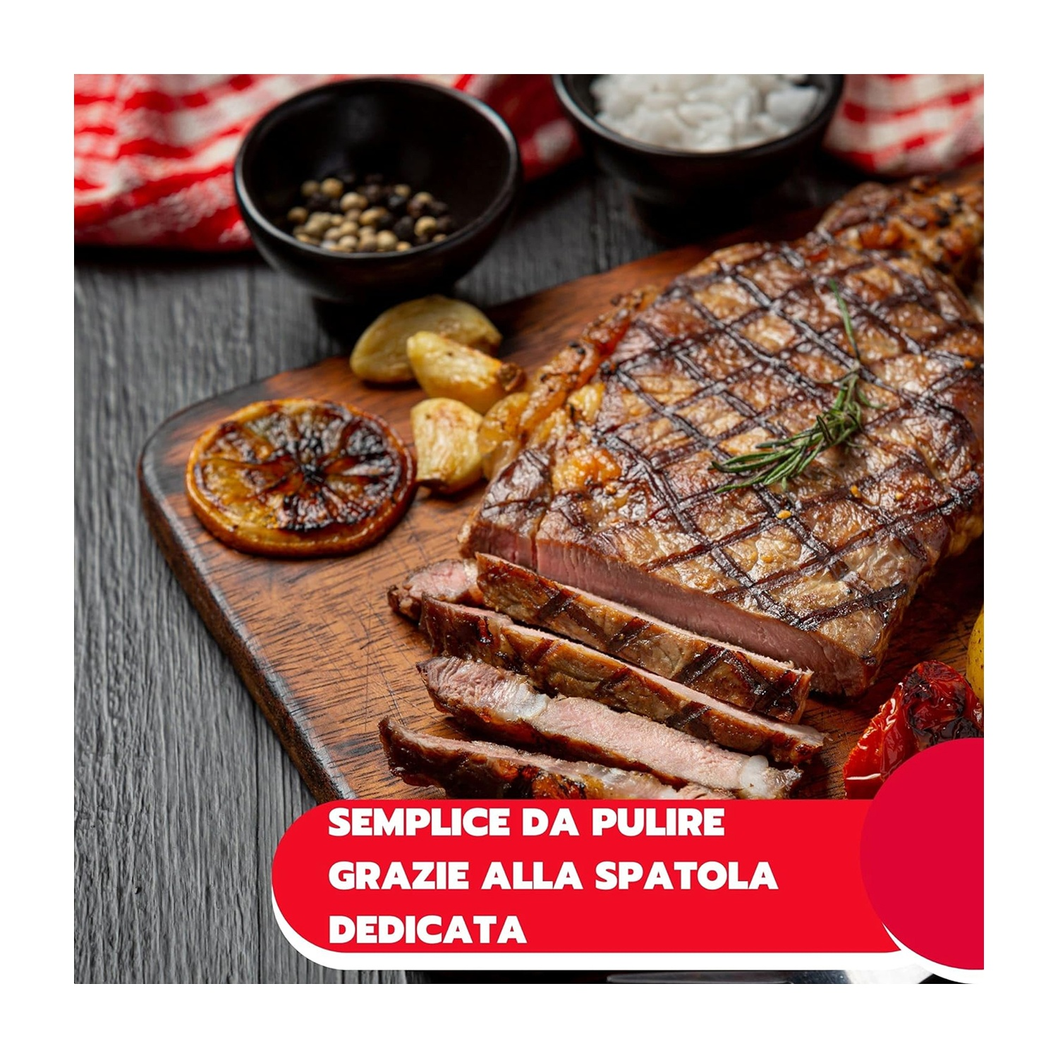 Bistecca alla griglia con fette, aglio e rosmarino su tagliere. Ciotole di sale e pepe sullo sfondo.