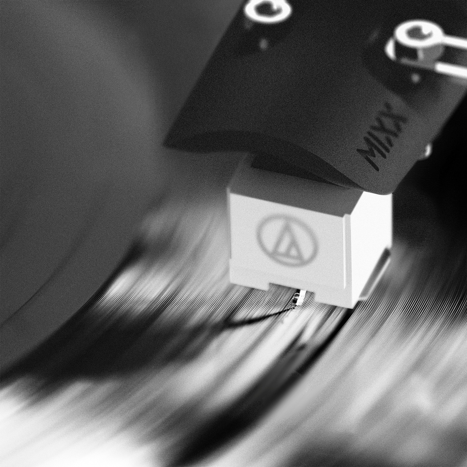 Een close-up, zwart-wit opname van een draaitafelnaald op een draaiende vinylplaat.