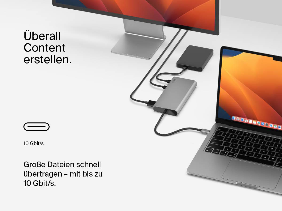 Ein Laptop ist mit Monitoren, externen Festplatten und anderen Geräten zur Datenübertragung verbunden.