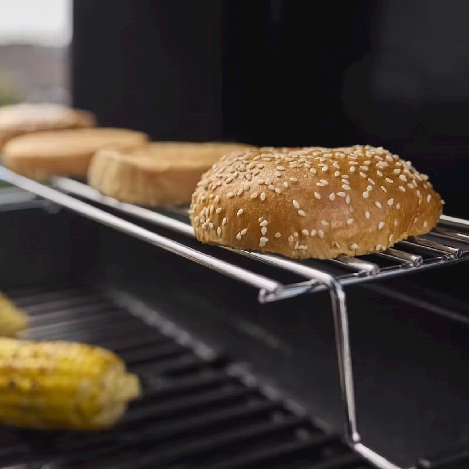 Un grill con panini ai semi di sesamo e pannocchie di mais.