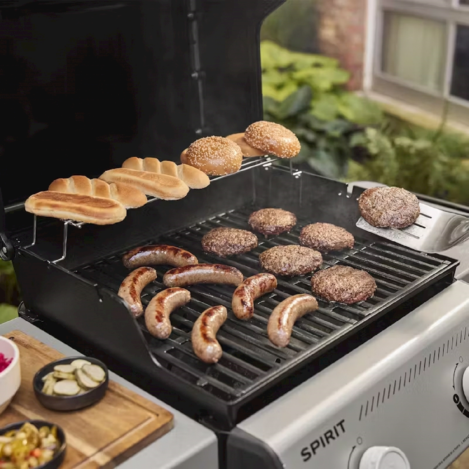 Un grill con salsicce, hamburger e panini sopra, con contorni e testo 'Spirit'.