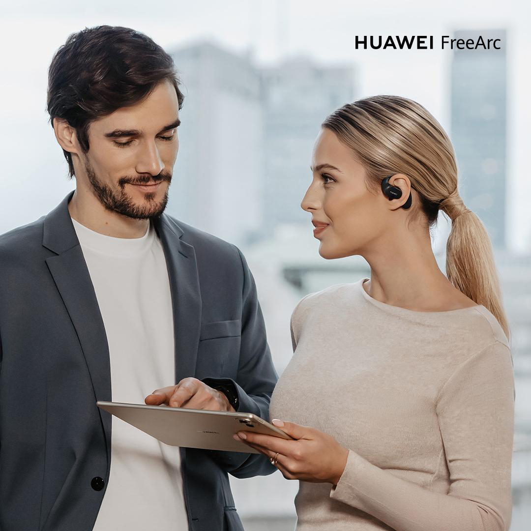 Ein Mann und eine Frau betrachten ein Tablet. Die Frau trägt Ohrhörer. Im Hintergrund sind ein Fenster und das Huawei FreeArc Logo zu sehen.
