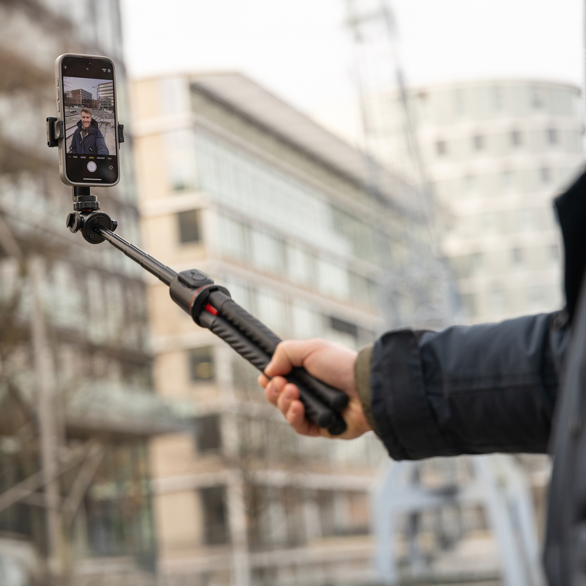 Una persona che tiene un telefono su un selfie stick all'aperto.