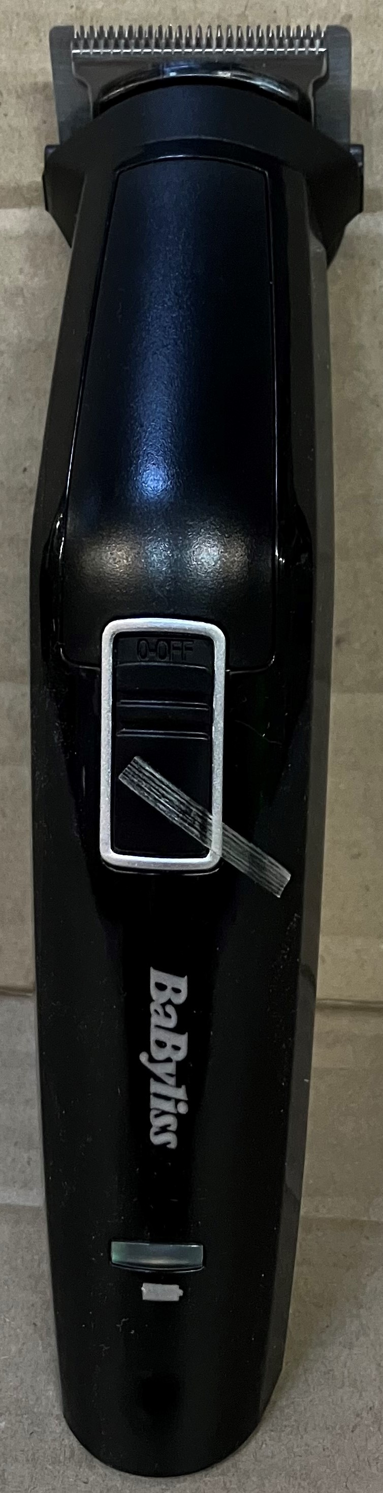 Czarny trymer do brody Babyliss. U góry ostrze, a na obudowie srebrny przycisk zasilania.